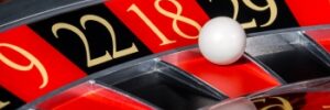 Close-up of a roulette wheel with the ball landing on red number 18, surrounded by adjacent black and red numbered sections.