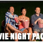 Three people sitting on chairs outdoors holding popcorn, smiling, with the text "Movie Night Packages!" at the bottom.