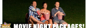 Three people sitting on chairs outdoors holding popcorn, smiling, with the text "Movie Night Packages!" at the bottom.