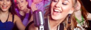 A woman sings into a microphone at a party, surrounded by four people dancing under colorful lights.