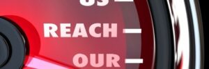 A speedometer-style gauge with text reading "HELP US REACH OUR GOAL!" on a red background.