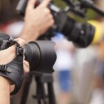 Photographers holding cameras with large lenses are capturing images outdoors.