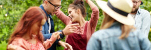 A group of people dancing outdoors at a festive gathering, with colorful bunting in the background.