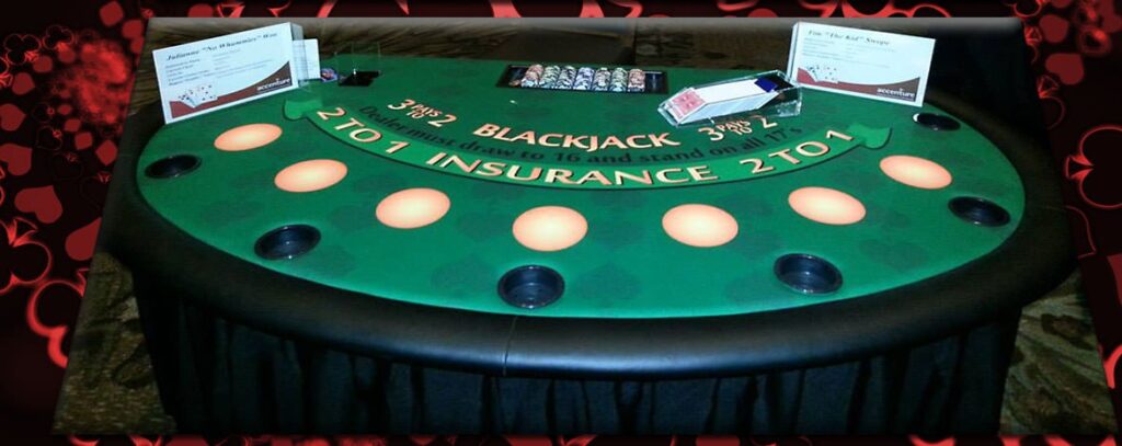 Green blackjack table with cards, chips, and signage listing rules and insurance payout details.